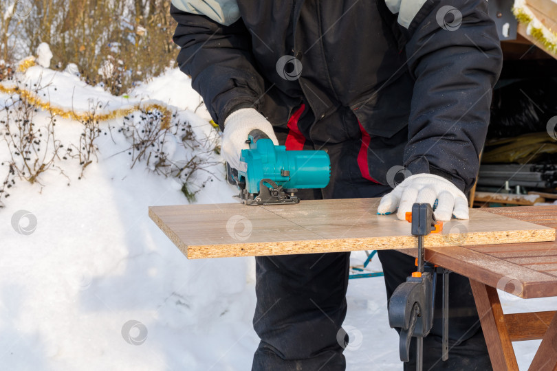 Скачать Рабочий режет деревянную панель на столе круглым инструментом фотосток Ozero