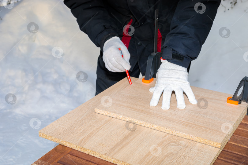 Скачать Мужчина, рабочий рисует карандашом на доске из ДСП. фотосток Ozero