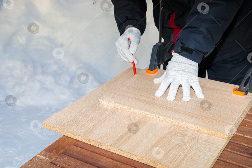 Скачать Мужчина, рабочий рисует карандашом на доске из ДСП. фотосток Ozero