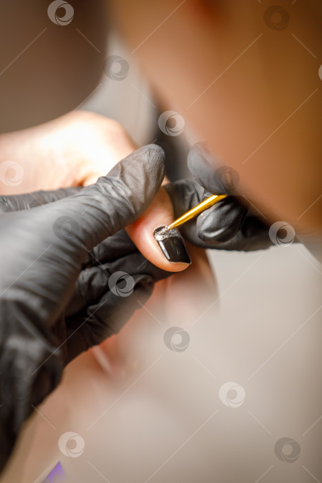 Скачать В студии красоты мастер делает маникюр, наносит кисточкой рисунок на ноготь. фотосток Ozero