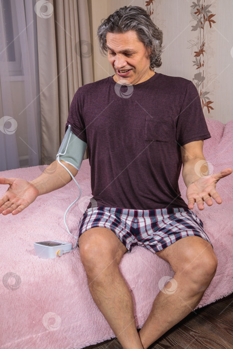 Скачать 50-летний мужчина измеряет свое кровяное давление с помощью тонометра. фотосток Ozero