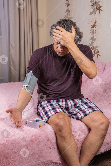 Скачать 50-летний мужчина измеряет свое кровяное давление с помощью тонометра. фотосток Ozero