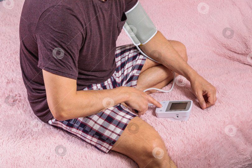 Скачать 50-летний мужчина измеряет свое кровяное давление с помощью тонометра. фотосток Ozero