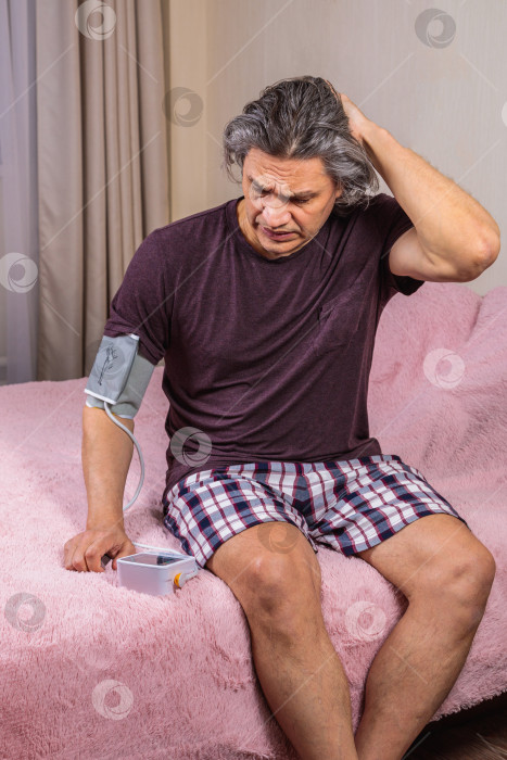 Скачать 50-летний мужчина измеряет свое кровяное давление с помощью тонометра. фотосток Ozero