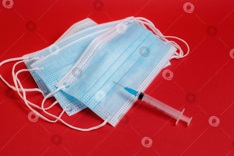 Скачать На столе лежит медицинская маска со шприцем и лекарством от коронавируса. фотосток Ozero