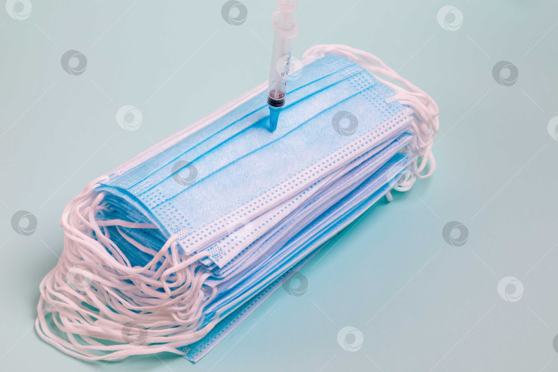 Скачать На столе лежит медицинская маска со шприцем и лекарством от коронавируса. фотосток Ozero