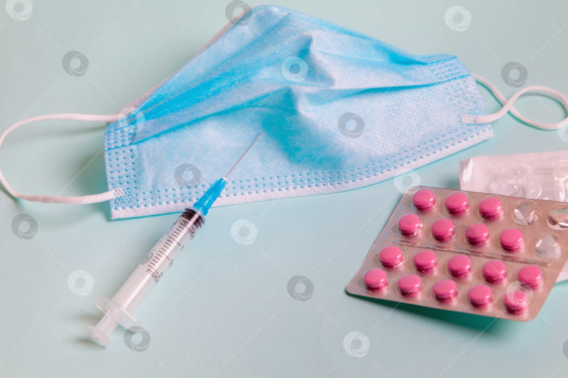 Скачать На столе лежит медицинская маска со шприцем и лекарством от коронавируса. фотосток Ozero
