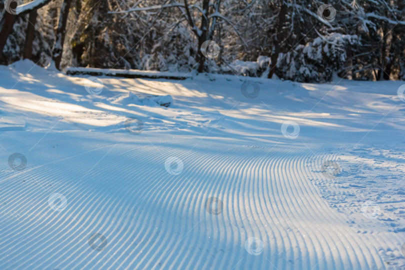 Скачать Плавные линии на лыжном склоне, оставленные снегоходом из ровных полос. фотосток Ozero
