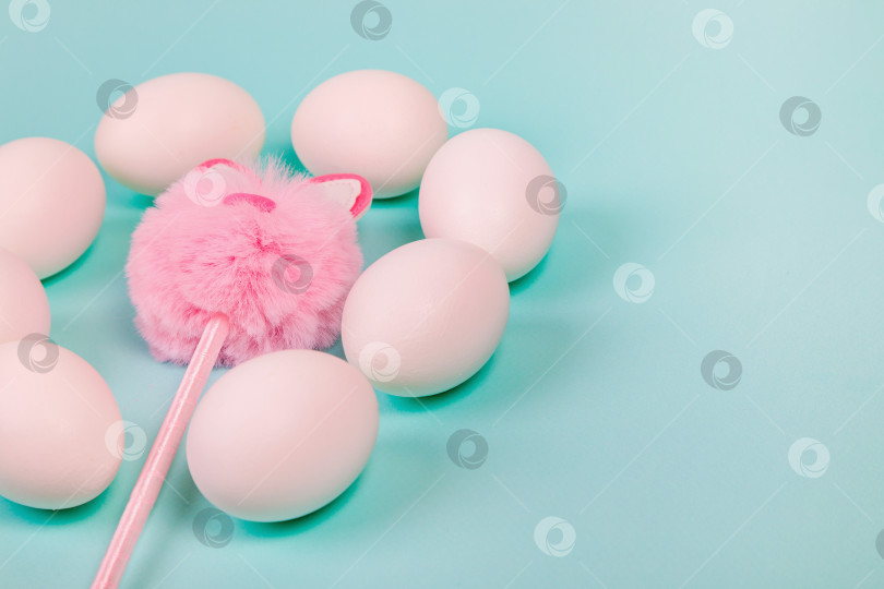 Скачать Пасха. Белые яйца с искусственным кроликом на однородном синем фоне. фотосток Ozero