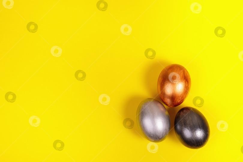 Скачать Разноцветные яйца на однородном желтом фоне с местом для текста. фотосток Ozero