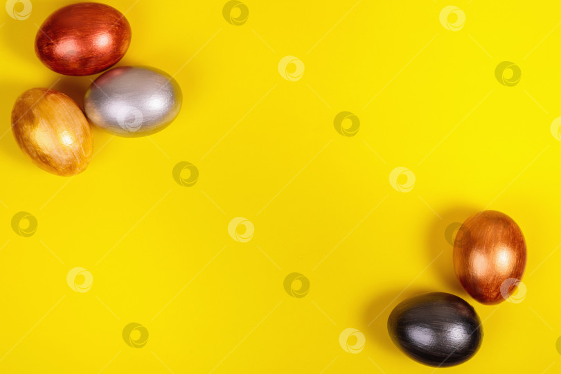 Скачать Разноцветные яйца на однородном желтом фоне с местом для текста. фотосток Ozero