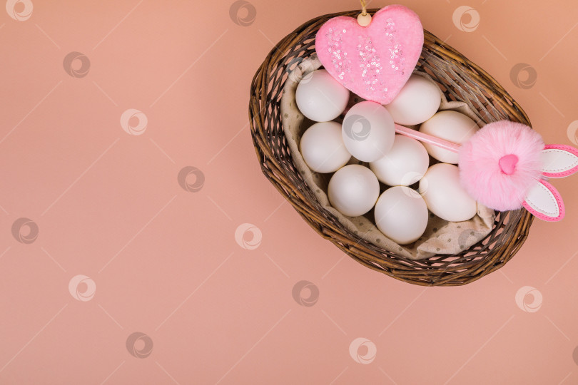 Скачать Пасха. Белые яйца в корзинке на однородном розовом фоне. Место для текста. фотосток Ozero