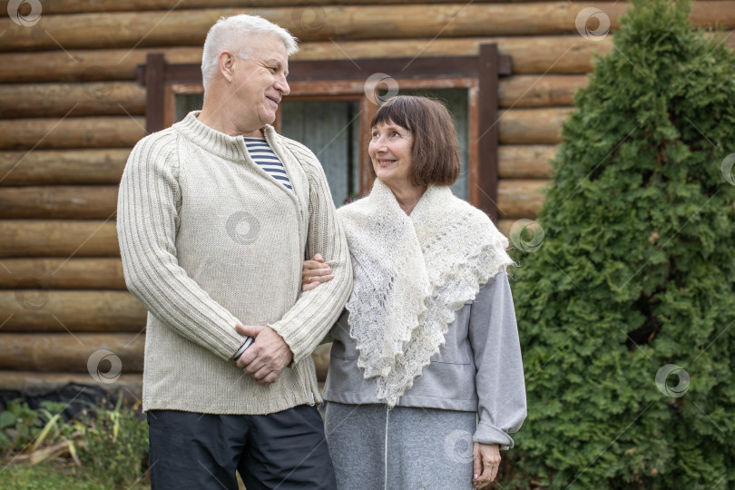 Скачать Деревенская пара пенсионеров позирует возле бревенчатой бани. фотосток Ozero