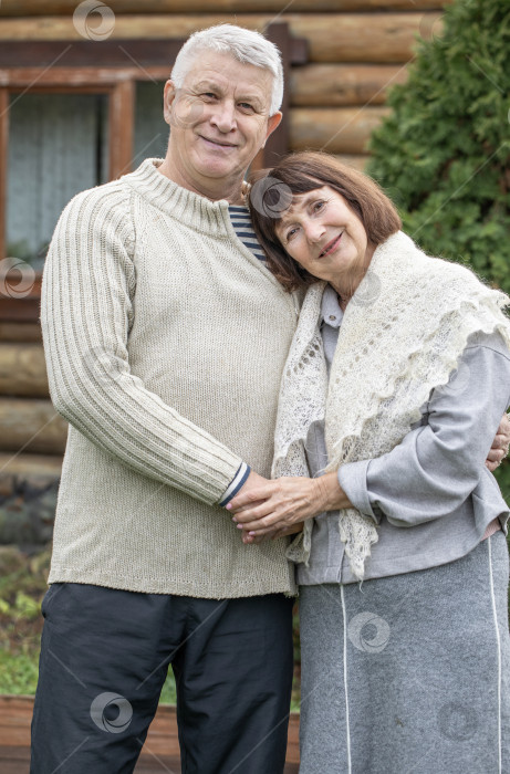 Скачать Деревенская пара пенсионеров позирует возле бревенчатой бани. фотосток Ozero