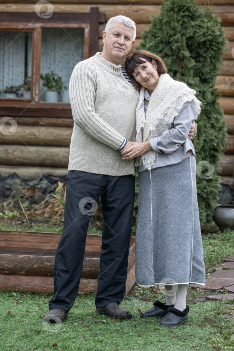 Скачать Деревенская пара пенсионеров позирует возле бревенчатой бани. фотосток Ozero