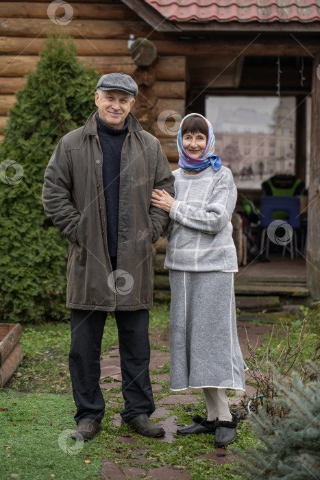 Скачать Деревенская пара пенсионеров позирует возле бревенчатой бани. фотосток Ozero