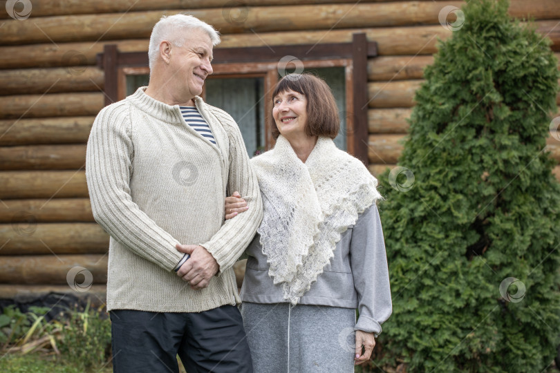 Скачать Деревенская пара пенсионеров позирует возле бревенчатой бани. фотосток Ozero