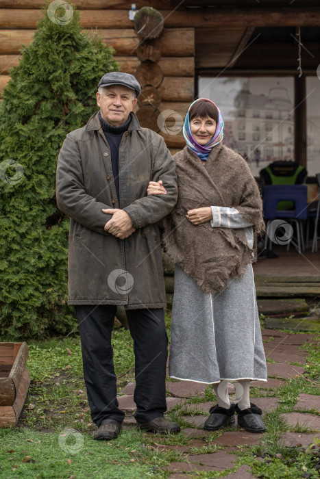 Скачать Деревенская пара пенсионеров позирует возле бревенчатой бани. фотосток Ozero