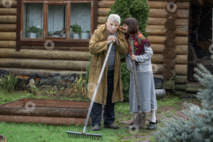 Скачать Деревенская пара пенсионеров позирует возле бревенчатой бани. фотосток Ozero