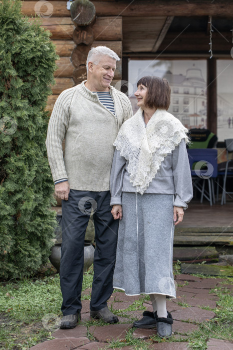 Скачать Деревенская пара пенсионеров позирует возле бревенчатой бани. фотосток Ozero