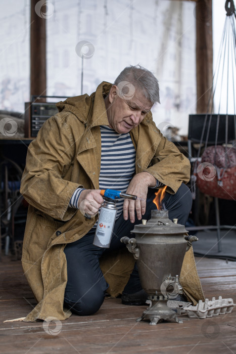 Скачать Деревенский крестьянин зажигает русский самовар фотосток Ozero
