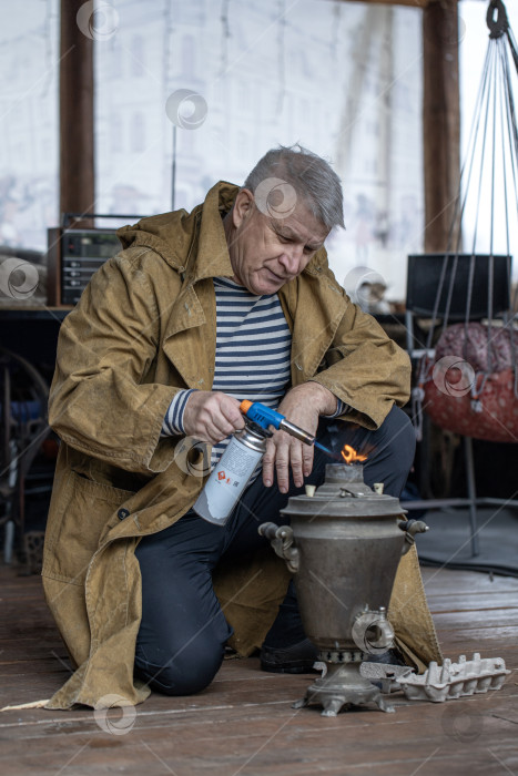 Скачать Деревенский крестьянин зажигает русский самовар фотосток Ozero