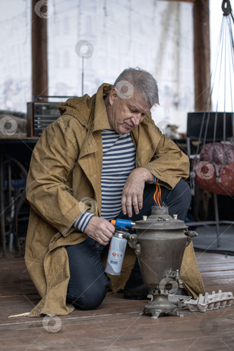 Скачать Деревенский крестьянин зажигает русский самовар фотосток Ozero