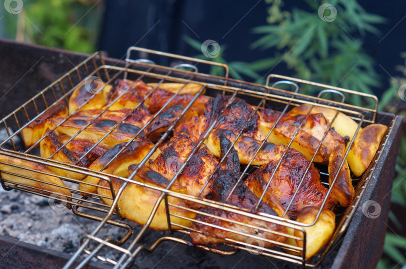 Скачать Кусочки курицы и картошки жарятся на решетке фотосток Ozero
