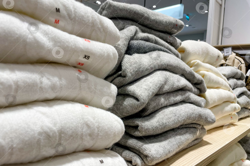 Скачать Одежда свитер джемпер разложена на полках шкафов купе в магазине торгового центра mall фотосток Ozero