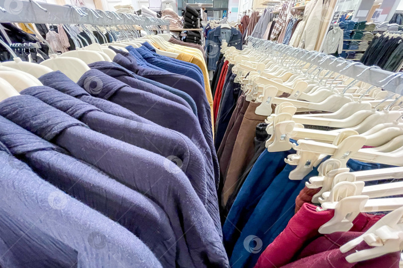 Скачать Тканевые платья, рубашки, брюки на вешалках в шкафах-купе в магазине shopping center mall фотосток Ozero