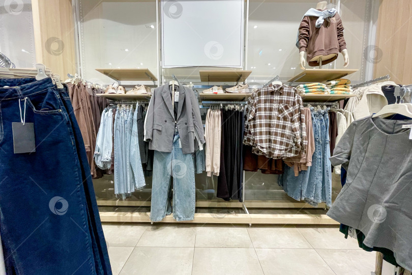 Скачать Тканевые платья, рубашки, брюки на вешалках в шкафах-купе в магазине shopping center mall фотосток Ozero