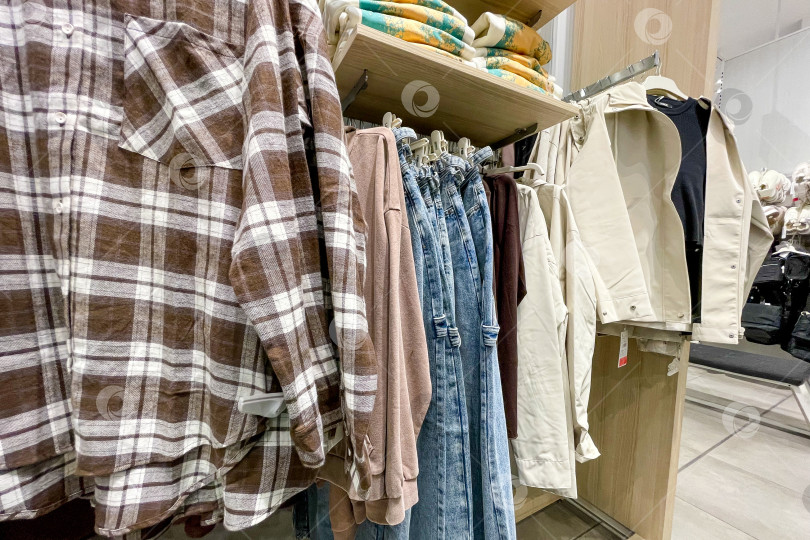 Скачать Тканевые платья, рубашки, брюки на вешалках в шкафах-купе в магазине shopping center mall фотосток Ozero