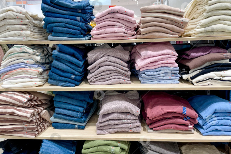 Скачать Одежда свитер джемпер разложена на полках шкафов купе в магазине торгового центра mall фотосток Ozero