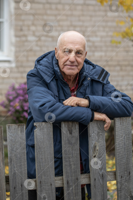 Скачать Одинокий сосед. Пожилой мужчина у деревянного забора фотосток Ozero