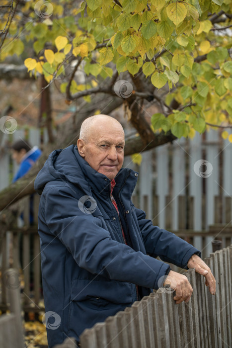 Скачать Бдительный сосед. Пожилой мужчина у деревянного забора фотосток Ozero