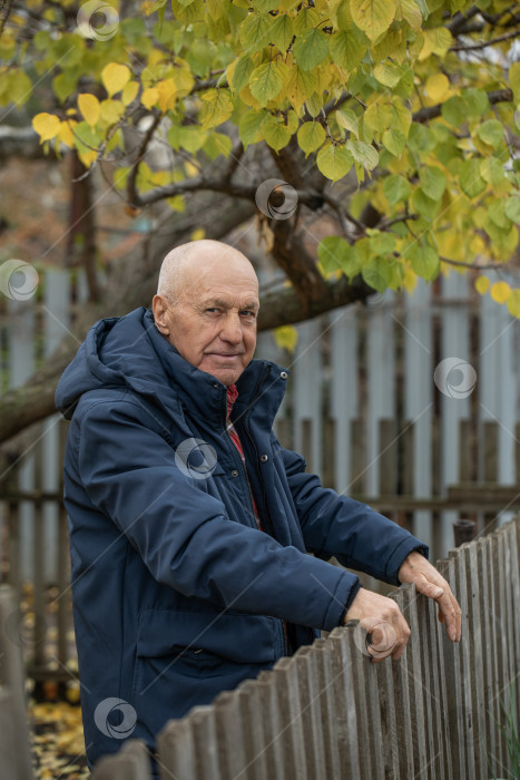 Скачать Одинокий сосед. Пожилой мужчина у деревянного забора фотосток Ozero