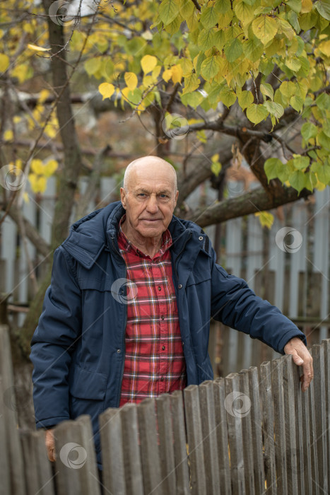 Скачать Одинокий сосед. Пожилой мужчина у деревянного забора фотосток Ozero