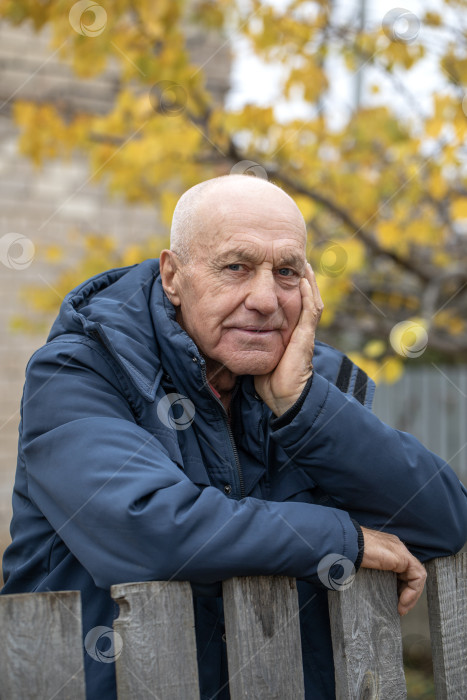 Скачать Одинокий сосед. Пожилой мужчина у деревянного забора фотосток Ozero