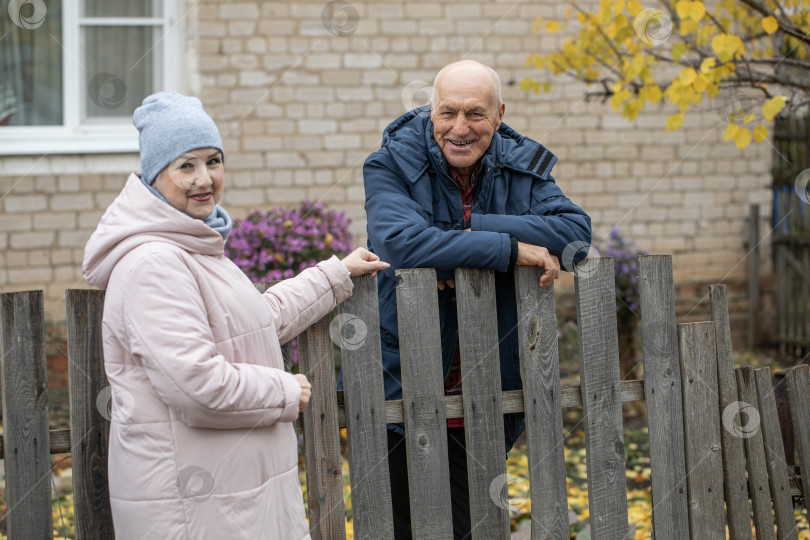 Скачать Соседи по даче. Пожилая пара у деревянного забора. фотосток Ozero