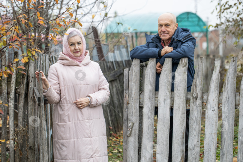 Скачать Соседи по даче. Пожилая пара у деревянного забора. фотосток Ozero