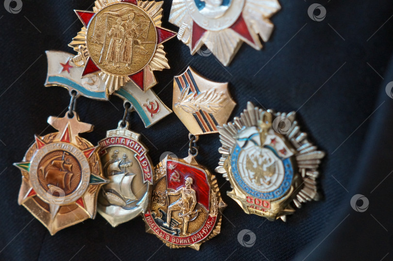 Скачать Саратов, Россия - 03 ноября 2025 года. Крупным планом ордена, значки и медали СССР времён Великой Отечественной войны: школа юнг, 25 лет победы в войне и другие фотосток Ozero