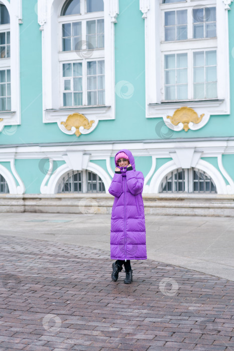 Скачать Женщина в фиолетовом пальто стоит перед зданием фотосток Ozero