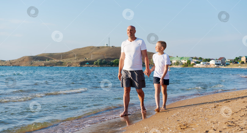 Скачать Мужчина и мальчик прогуливаются по пляжу фотосток Ozero