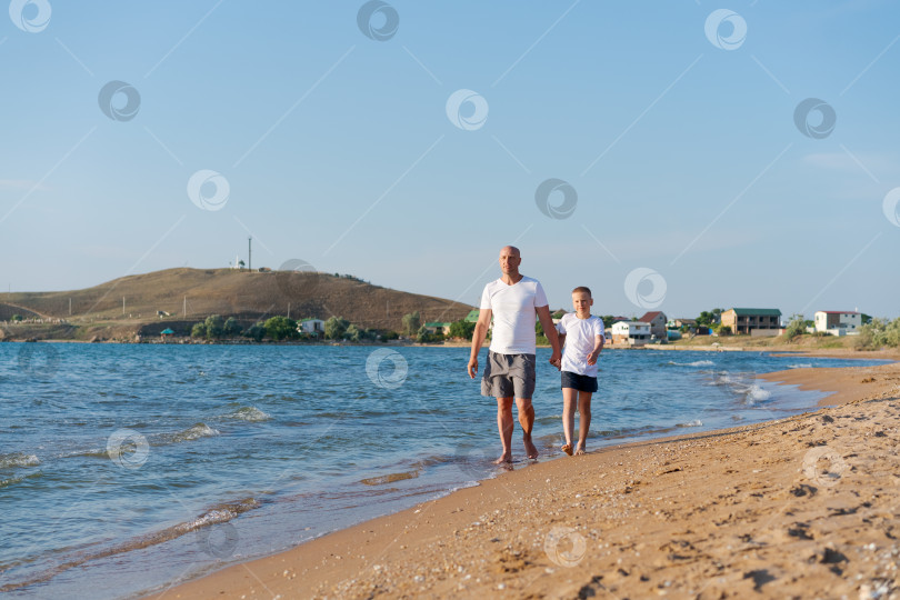Скачать Мужчина и ребенок прогуливаются по пляжу фотосток Ozero