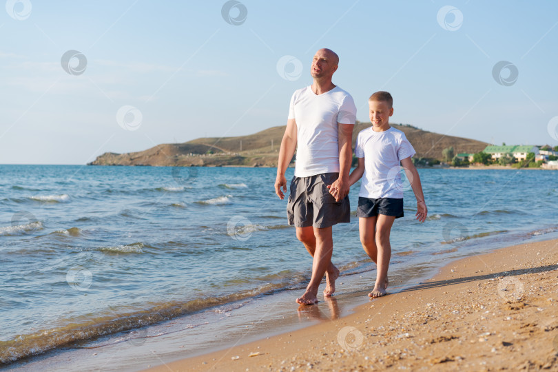 Скачать Мужчина и мальчик прогуливаются по пляжу фотосток Ozero
