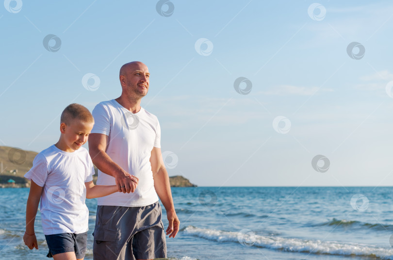 Скачать Мужчина и мальчик прогуливаются по пляжу фотосток Ozero