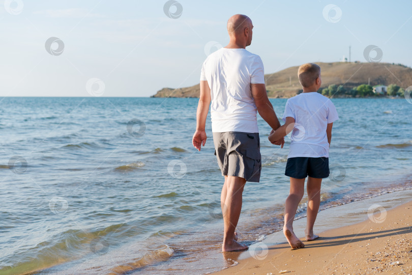 Скачать Мужчина и мальчик прогуливаются по пляжу фотосток Ozero