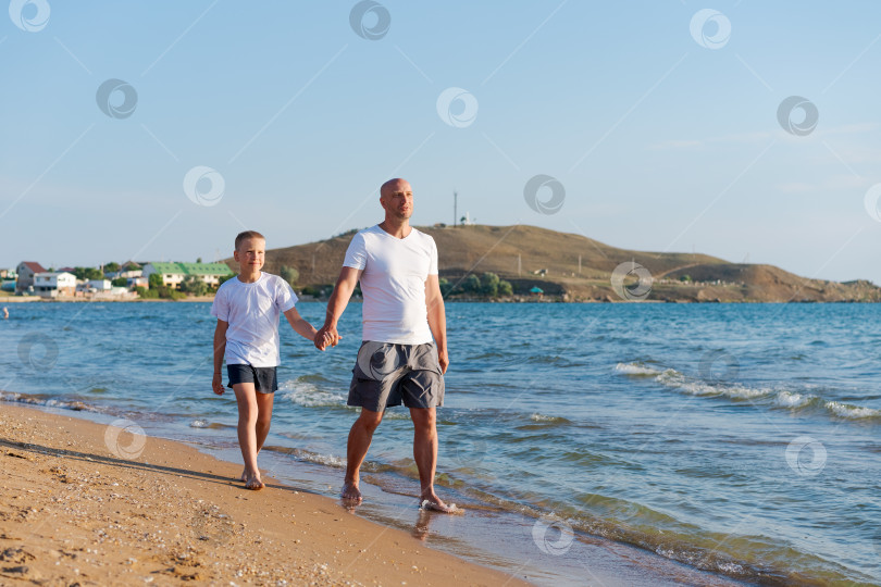 Скачать Мужчина и мальчик прогуливаются по пляжу фотосток Ozero