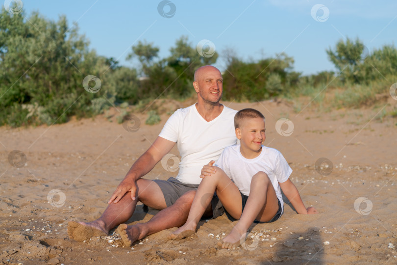 Скачать Мужчина и мальчик сидят на пляже фотосток Ozero