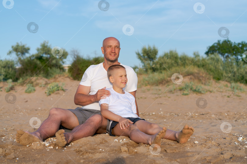 Скачать Мужчина и мальчик сидят на пляже фотосток Ozero